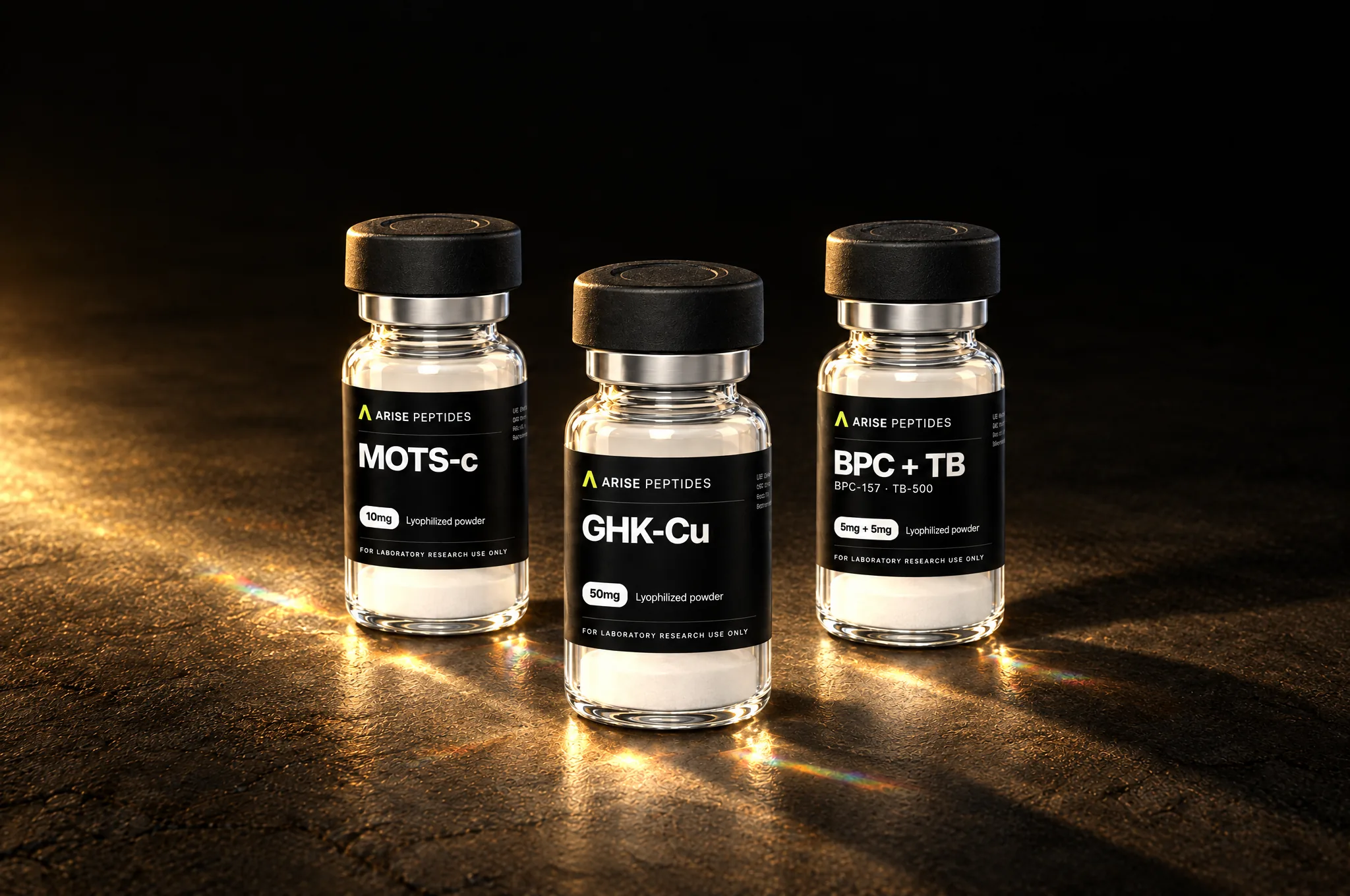 ArisePeptides MOTS-c, GHK-Cu and BPC + TB research vials on a dark stone surface in warm light